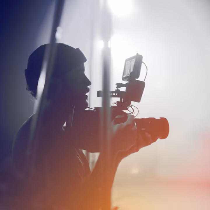 Silhouette of a person filming with a professional camera against bright backlight.