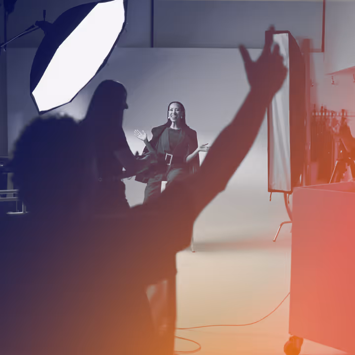 Photographer and crew directing a smiling woman posing in a professional photo studio.