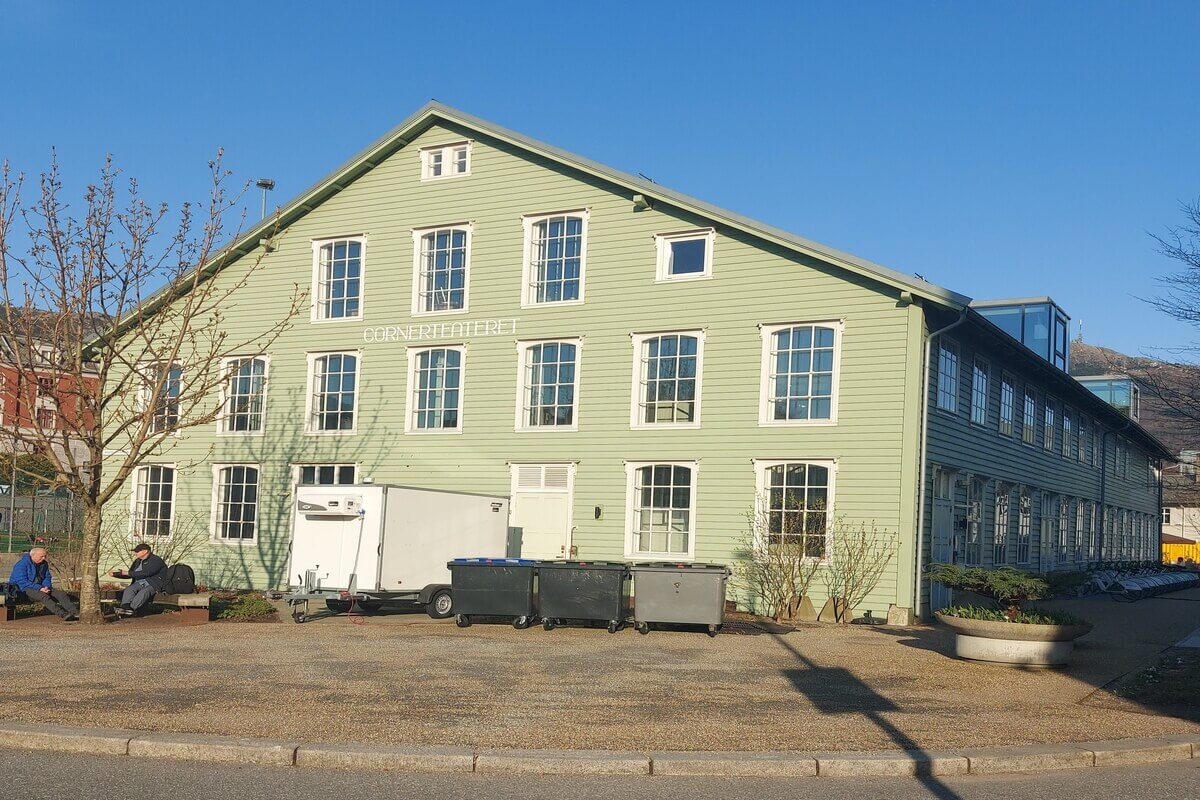 Cornerteateret i Bergen, stor grønn bygning med mange vinduer sett fra baksiden mot en blå himmel