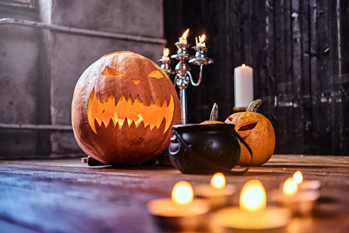 Utskårne gresskar og en lysekrone med levende lys som illustrasjonsbilde for arrangementsbeskrivelsen av Halloweenhuset på Det Vestnorske Teateret