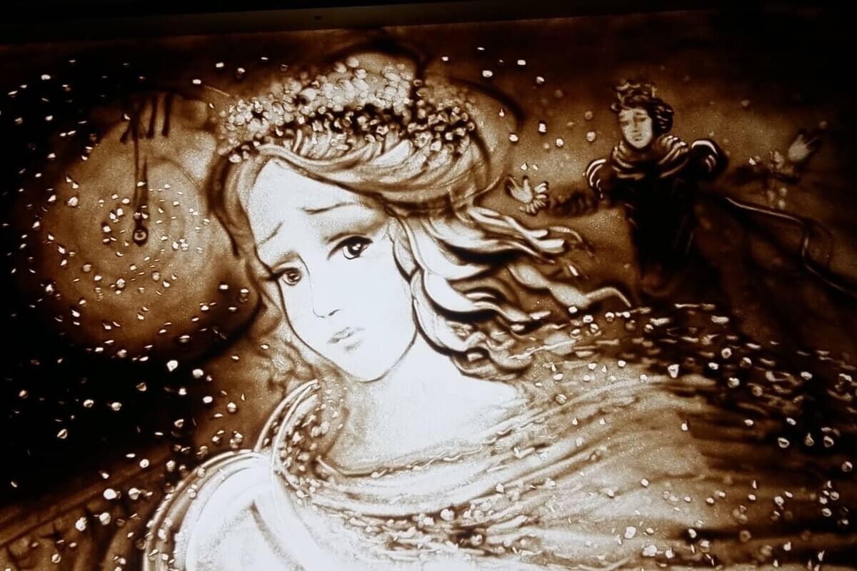 Et kvinnehode med en mann i bakgrunnen tegnet i mørk sand som illustrasjon for sandkunst med Lysteater