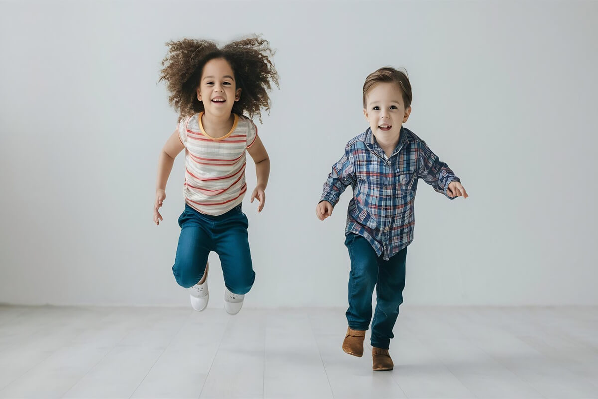 En gutt som hopper med beina krøllet opp, en annen som løper mot kamera i et gråmalt lokale som illustrasjonsbilde for familiedans med Takeshi Matsumoto på Elefantteateret