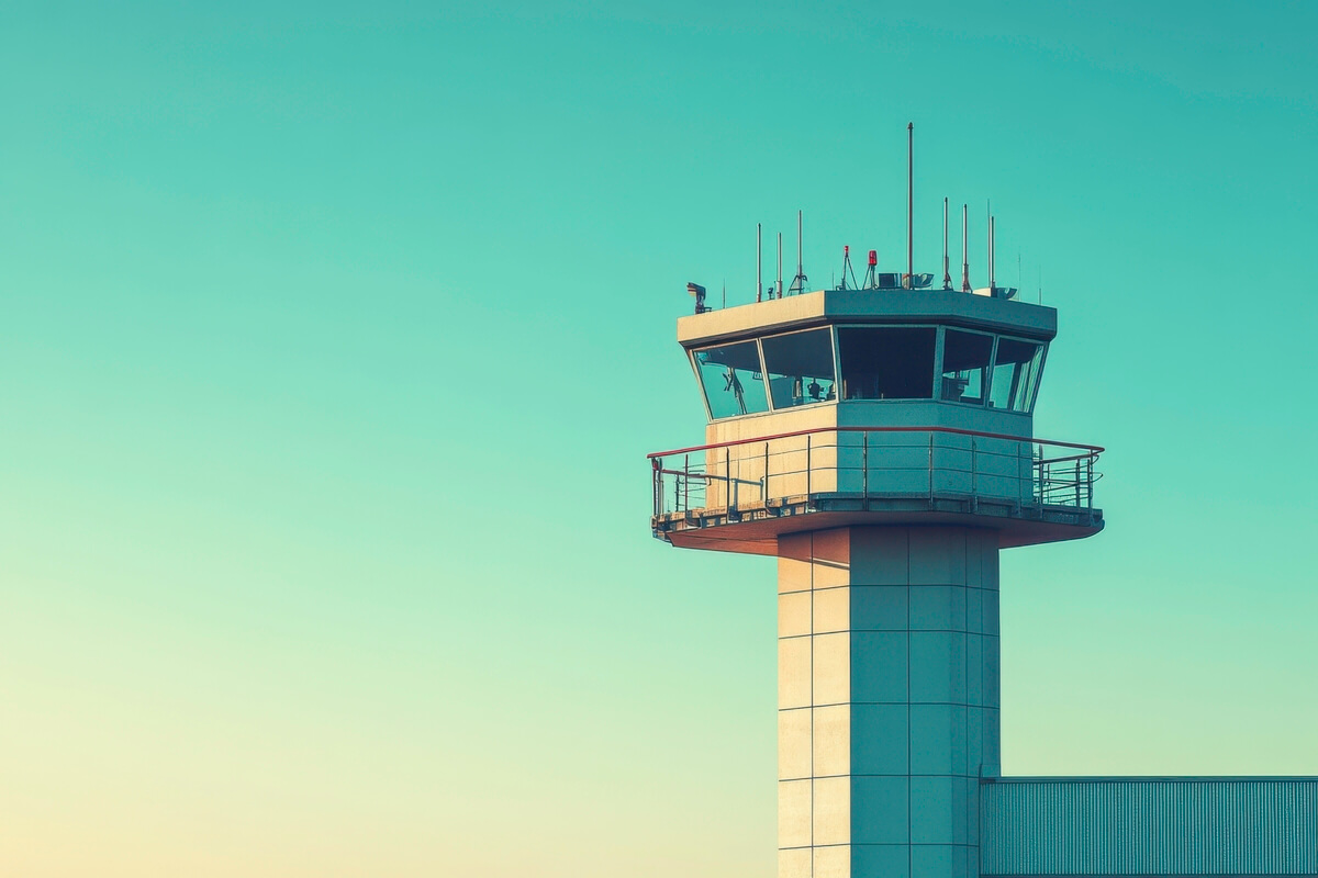 Kontrolltårn med moderne design under en klar blå himmel. Bildet viser tårnets vinduer og antenner, omgitt av en varm solnedgangsfarge