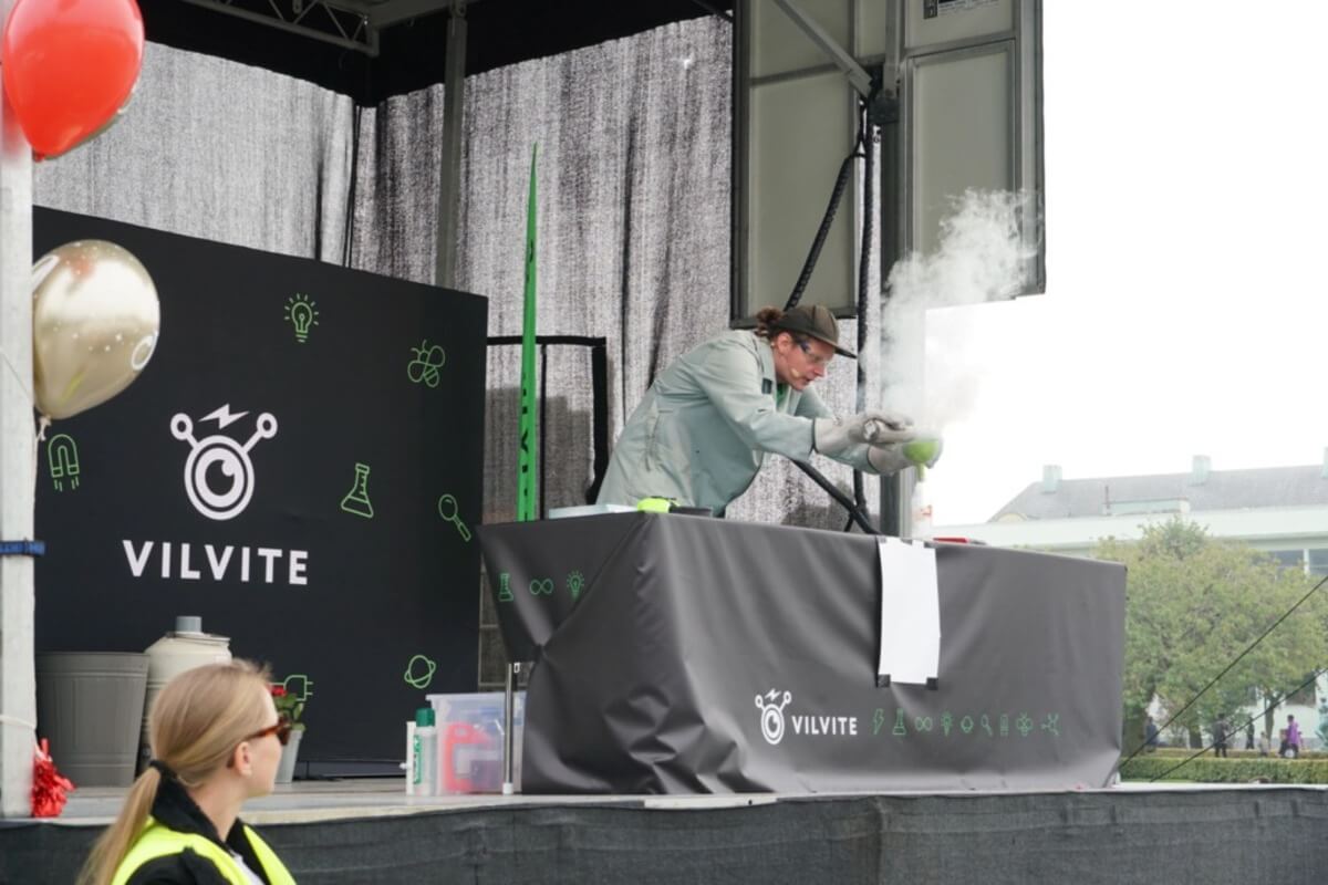 En formidler fra VilVite holder vitenshow på scenen under Forskningstorget i Bergen, med røykende kjemieksperimenter som fascinerer publikum
