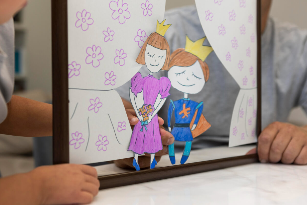 Barn leker med papirfigurer av en prins og prinsesse i et hjemmelaget dukketeater