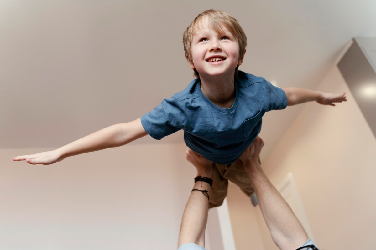 Gutt som blir holdt på strake hender over hodet på farsen sin som illustrasjonsbilde for familiedans for barn med funksjonsvariasjoner på Elefentteateret