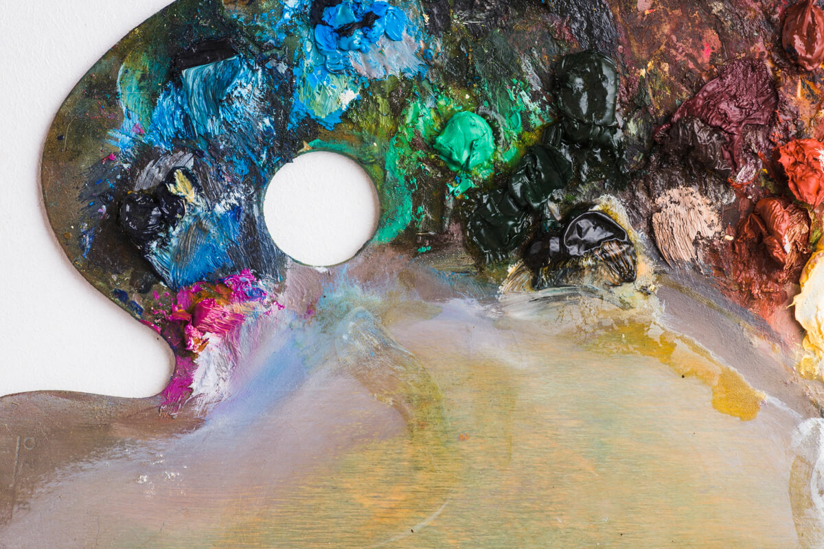 Nærbilde av en kunstnerpalett med fargerike malingsklatter i blått, grønt, rødt og gult