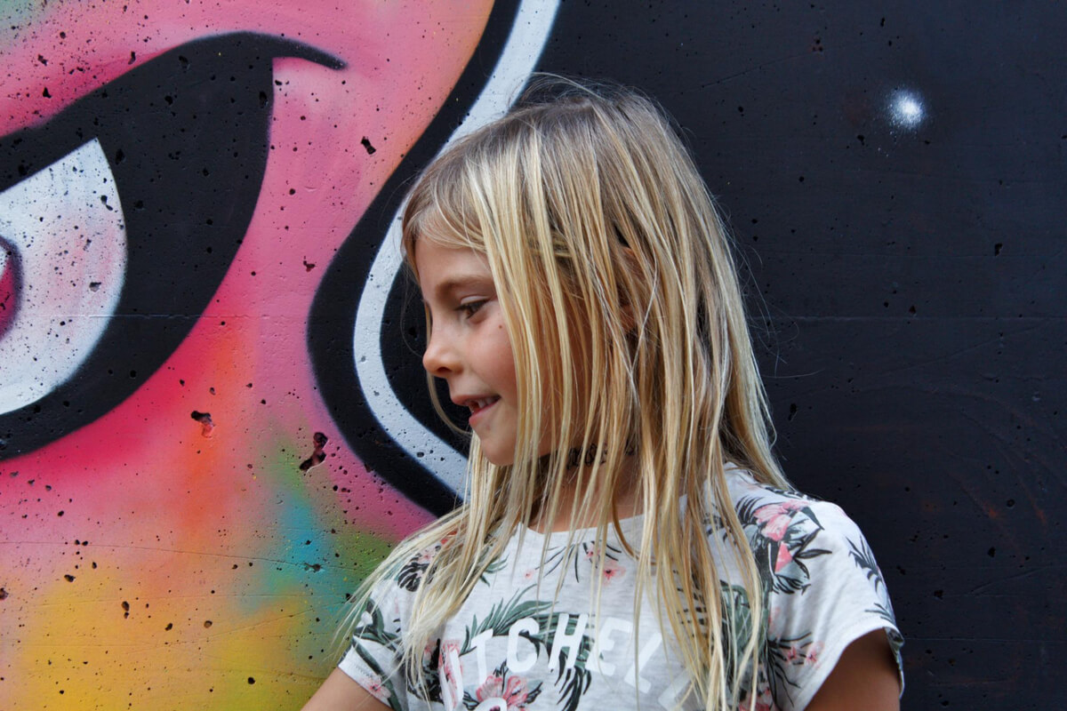 Illustrasjon av et barn foran en fargerik graffiti-vegg, brukt som illustrasjonsbilde i forbindelse med kulturaktiviteter for barn og familier i Tromsø kulturhus.