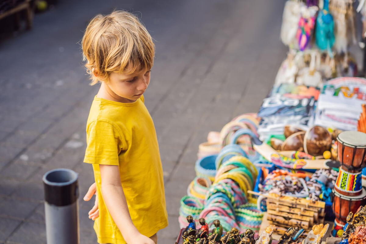 Gutt med gul t-shirt som ser på produkter i en bod som illustrasjonsbilde for familiedagen under Porsgrunn Internasjonale Teaterfestival