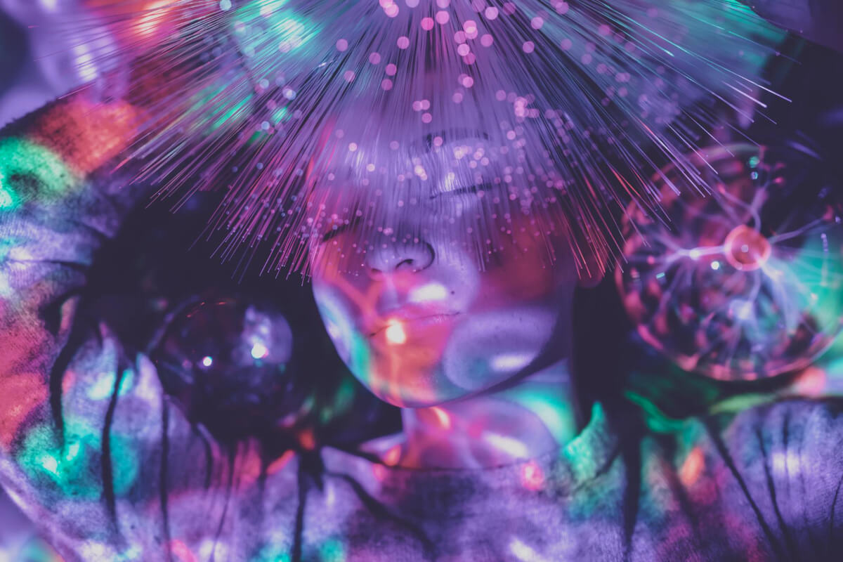 Et barn ligger omgitt av fargerike lys og fiberoptiske effekter som skaper en drømmende stemning, som illustrasjonsbilde for beskrivelsen av Union Scene for Barn