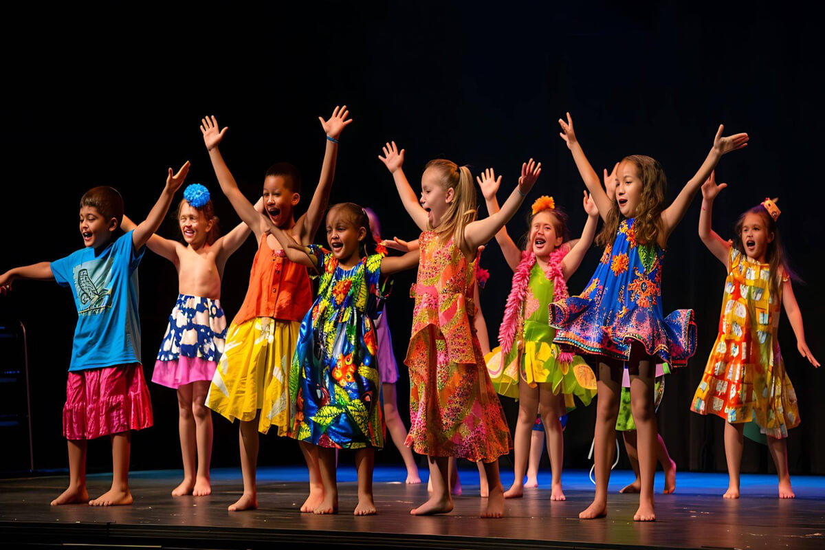 En gruppe barn i fargerike kostymer synger og danser sammen på en scene
