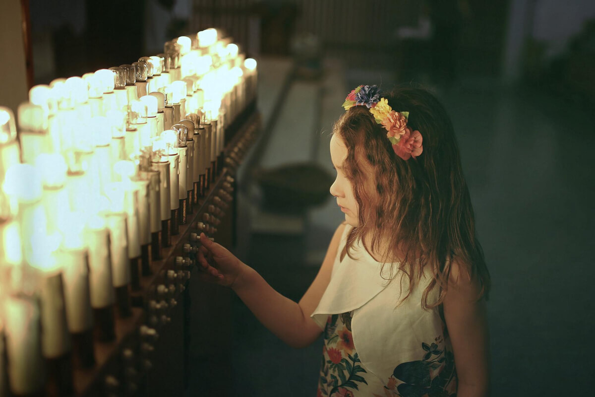 Jente med hårkrone foran en rekke med stearinlys som illustrasjon til vandreteater med Eventyr i Parken i Nygårdsparken