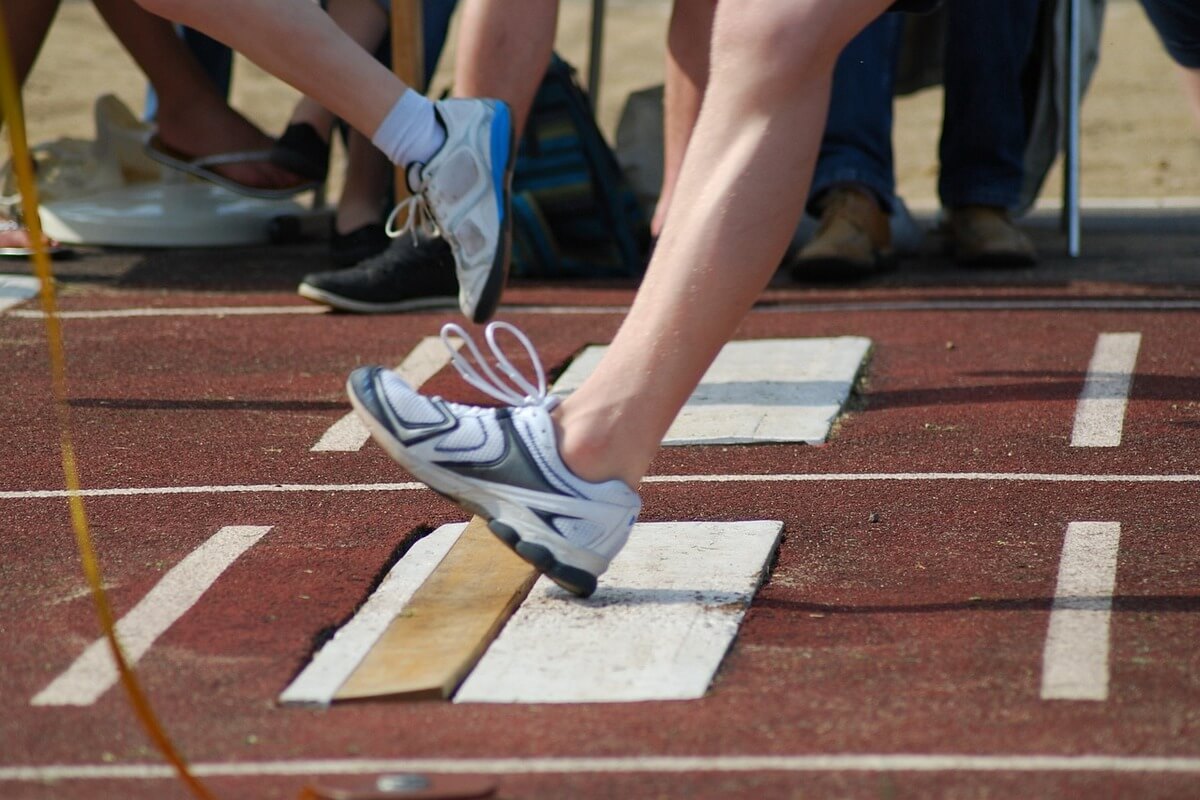 Ben med løpesko som trår planken ved lengdehopp som illustrasjonsbilde for Barnas Bislettdag