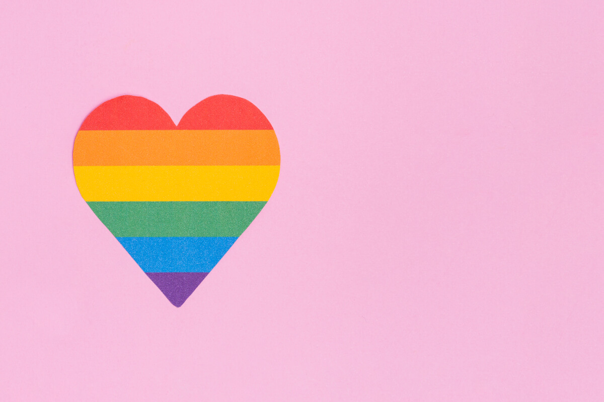 Hjerte med Pride farger  mot en pink bakgrunn som illustrasjonsbilde for regnbuefrokost hos Kunst Kraft i Tønsberg