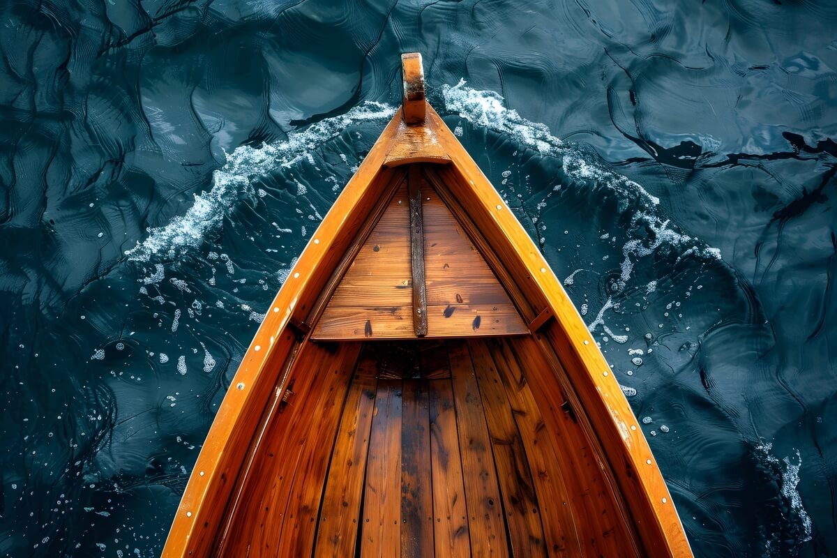 En tradisjonell åpen trebåt sett ovenfra skjærer gjennom mørkt vann