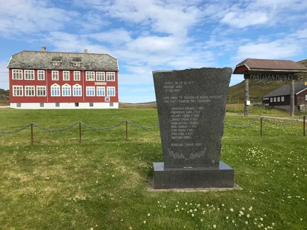 Partisanmuseet i Kiberg kjennetegnet med sin røde farge og mange vinduer med minnestein over falne i forgrunnen