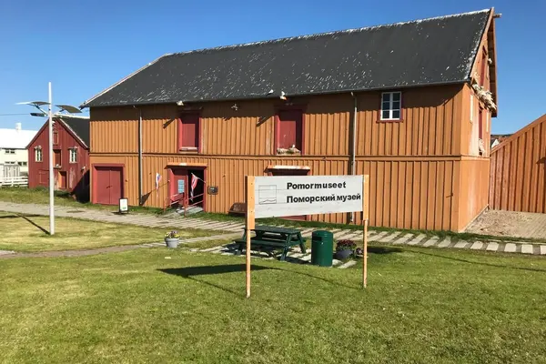  Pomormuseet sett utenfra med velkomsskilt på gressplenen foran bygningen