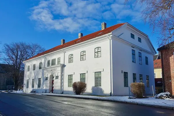 Lang fleretasjers bygning i betong med mange vinduer og rødt teglsteinstak, som rommer Justismuseet 