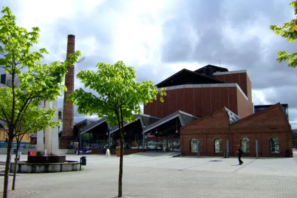 Sandnes kunst- og kulturhus, rød stor musteinsbygning med mindre utbygg i gateplan, fotografert fra plassen foran huset