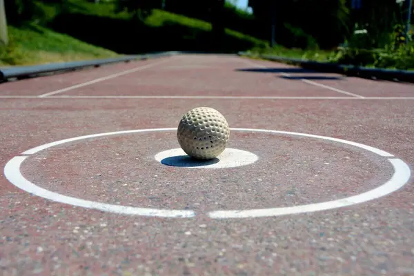 Golfball plassert i sentrum av en hvit sirkel på en betongbane 