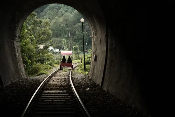 Dresin med to personer på vei ut av en tunnel, fotografert inne fra tunnelen