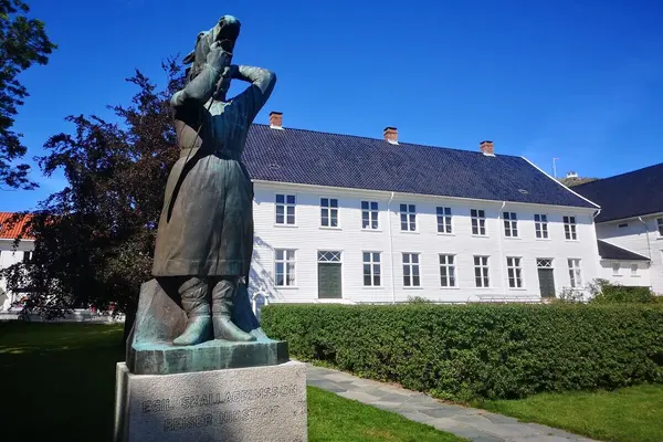 Andorsengården, stor hvit kjøpmannsgård med svart tak og velpleiet hage foran, huset rommer Mandal museum