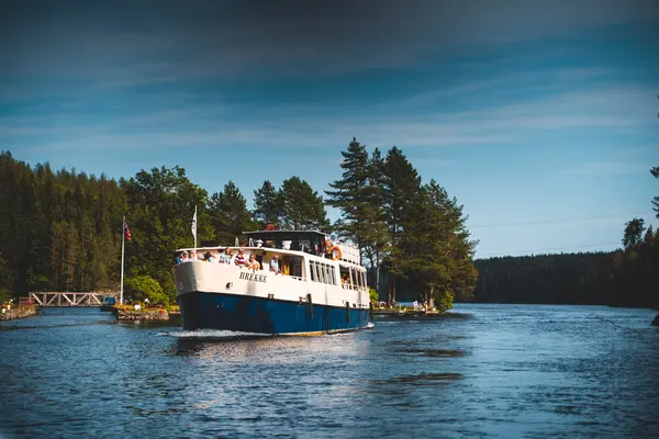 M/S Brekke på Haldenkanalen, blått og hvitt skrog og langt overbygg med mange vinduer 