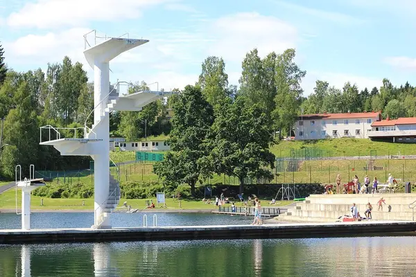 Sylinderformet hvitt stupetårn med to avsatser på en utstikkerbrygge i Hovdevannet ved Fastland friluftsbad i Gjøvik