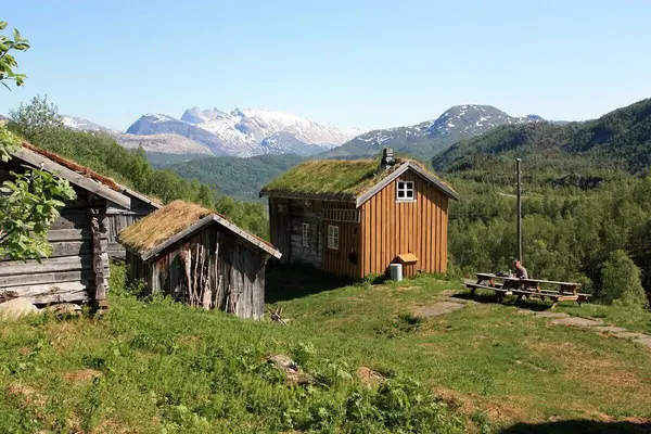 Et eldre gulmalt trehus med torvtak og noen eldre naturfargede løer og uthus på husmannsplassen Kjelvik plassert på toppen av en skrent og med et vilt og flott landskap i horisonten 