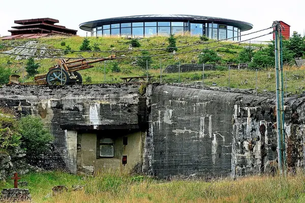 Kanontårnet på Fjell festning, en sirkelrund lav glassbygning, på toppen av et bunkersanlegg fotografert mot inngangen