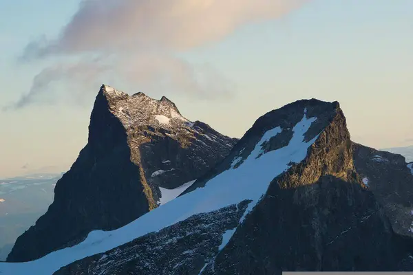 To fjelltopper som se rut som en V mot hverandre, det nærmeste delvis snødekket