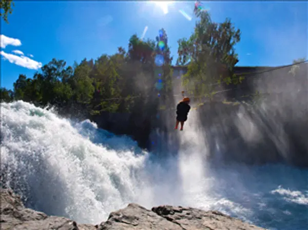 Person i zipline over frådende fossestryk