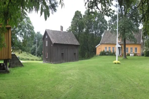 Gårdstunet på Huseby gård, som huser Skedsmo Bygdemuseum, en naturfaget toetasjes låve og et gulfarget hovedhus 