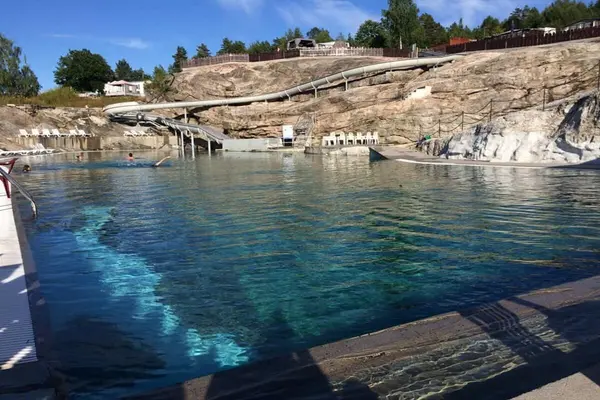  Utendørs saltvannsbasseng med vannsklie som snor seg ned over svabergene i bakgrunnen på Lovisenberg Familiecamping i Kragerø