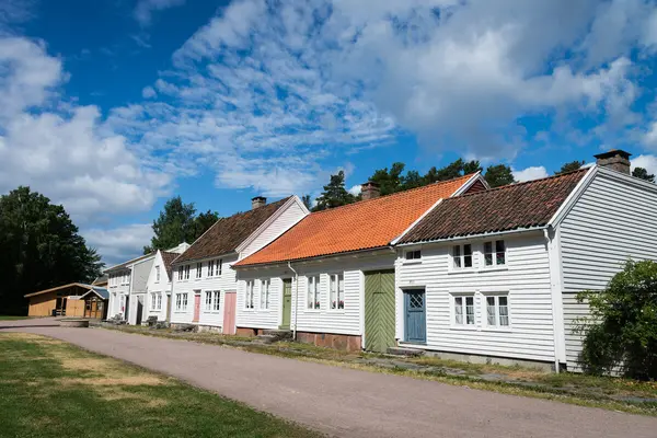 Bygaden på Kristiansand museum, en rekke med fem sammenbygde hvitmalte hus i forskjellig høyde og form, alle med tegltak, og en grusvei som går foran husene 
