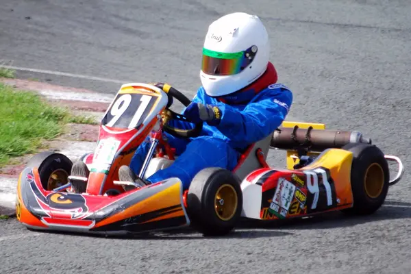  Gokart med sjåfør med hvit hjelm og blå drakt i nærbilde