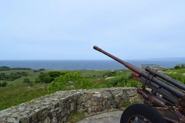 Landskapet på Nordberg fort med havet i bakgrunnen og en kanon på en kanonstilling i forgrunnen