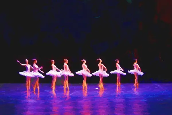 Åtte ballettdansere i hvite skjørt på en rekke på et blåfarget scenegulv og svart bakgrunn som illustrasjonsbilde beskrivelsen av balletten Nøtteknekkeren på Den Norske Opera & Ballett 