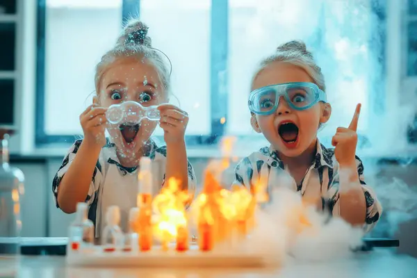 To jenter med åpne munn og skrekk i ansiktet bak flammer på et bord etter et eksperiment som illustrasjonsbilde for beskrivelsen av Vitenshitshow på Lillestrøm Kultursenter