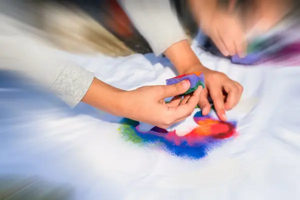 Barn som lager fargerike kunstprosjekter med svamp og maling, brukt som illustrasjonsbilde til beskrivelsen av familieverkstedet på Astrup Fearnley Museet
