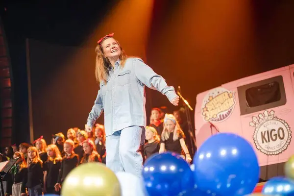 SaraLy på scenen med plakat med KIGO-logo