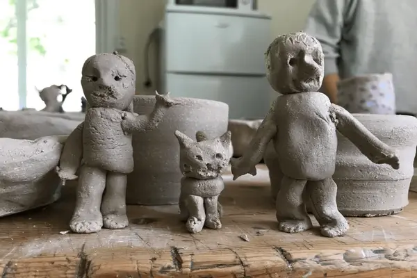 Tre keramikkfigurer i grått, to menn med en hund i mellom seg som illustrasjon til Barnetime-kurs i Franz Klammer Keramikkverksted