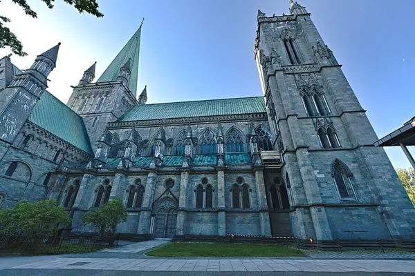 Den vestlige delen av Nidarosdomen med et av tårnene til høyre i bildet og midtpartiet med spiret til venstre i bildet med skyfri himmel over kirken