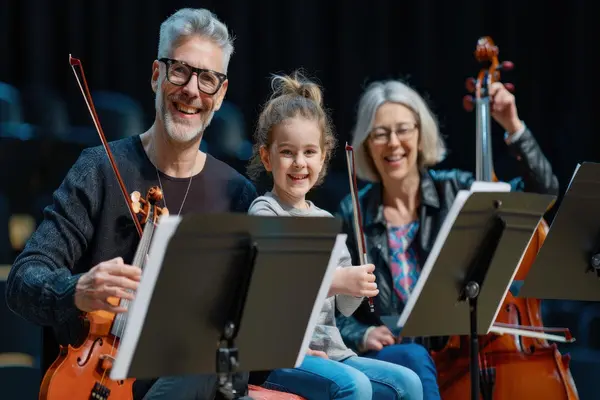 Smilende barn og voksne med strykeinstrumenter i orkester, som illustrasjonsbilde for beskrivelsen av familiedagen med Oslo-Filharmonien i Oslo Konserthus
