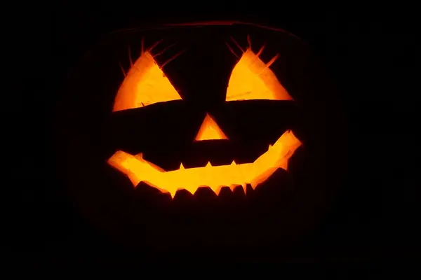 Lysende gresskarøyne, -munn og -nese mot en mørk bakgrunn, som illustrasjonsbilde for beskrivelsen av Halloween på Nasjonalmuseet i Oslo