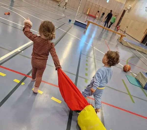 To små barn i en treningshall som sleper på hver sin myke bag som illsutrasjon til Akrolørdag på Bekkestua