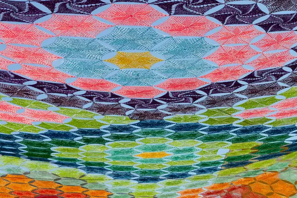 Fargerikt, geometrisk tekstilmønster med gjentakende former i blått, grønt, rødt, gult og rosa, som skaper et rytmisk og sanselig uttrykk, som illustrasjonsbilde av beskrivelsen for Babyomvisning på Interkulturelt Museum