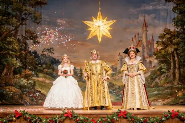 Skuespillere i eventyrkostymer står på scenen under en teaterforestilling med en lysende julestjerne og slottskulisser i bakgrunnen, som illustrasjonsbilde for beskrivelsen av Reisen til Julestjernen på Kilden i Kristiansand