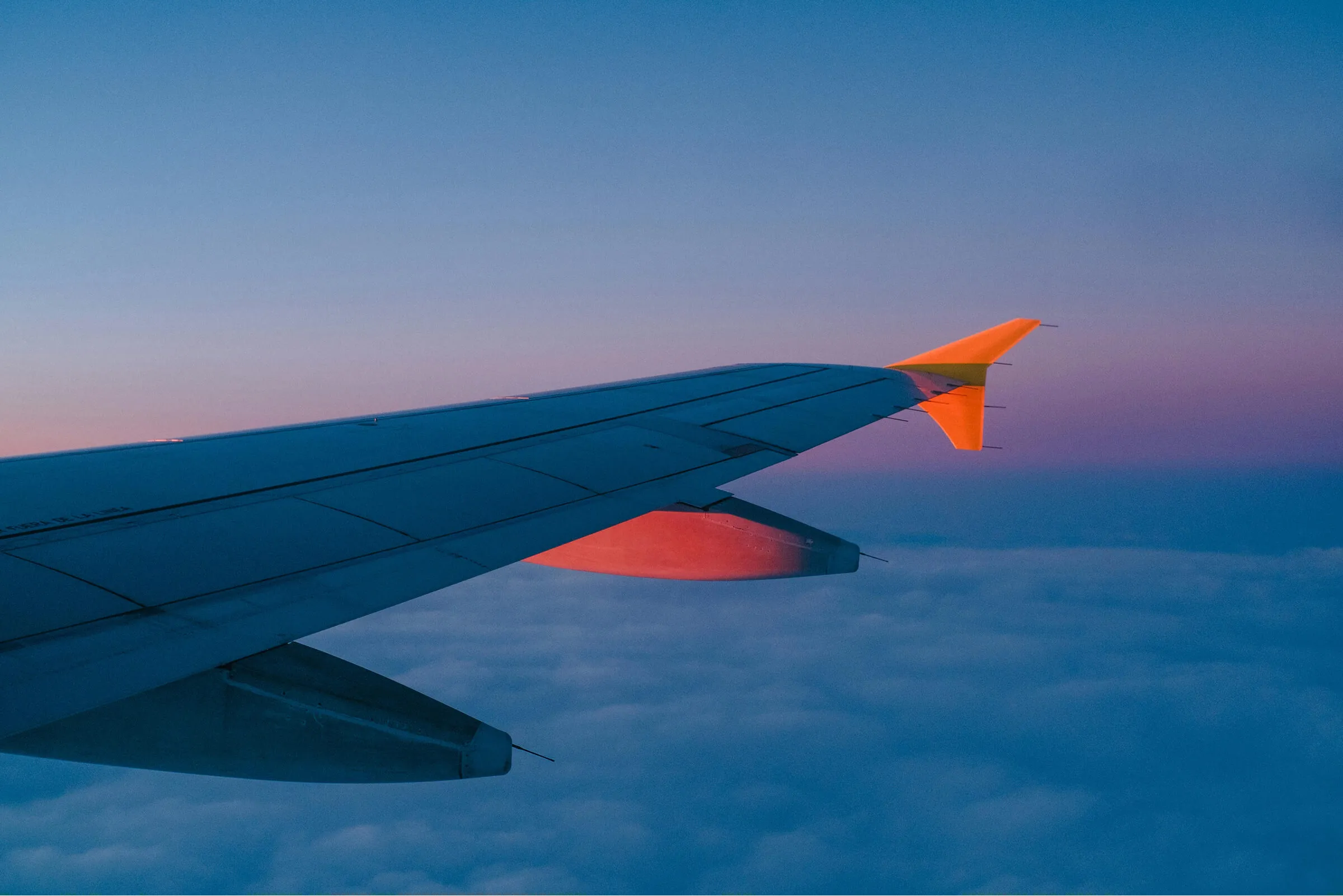 Airplane wing over white clouds