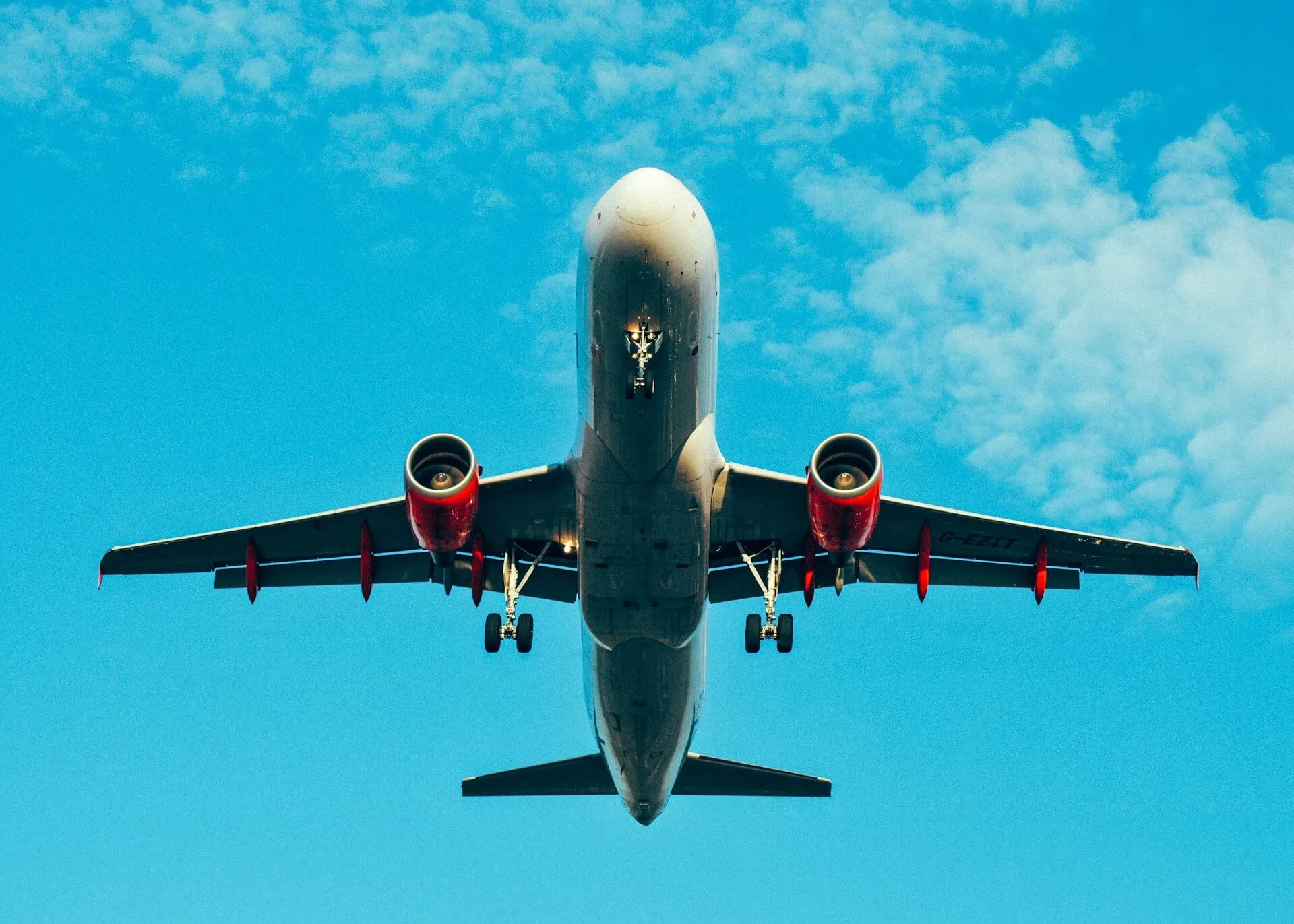 airplane flying overhead in a bright blue sky